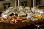 gold and silver bullion on a table in front of safe