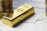 gold bar and coins on financial papers